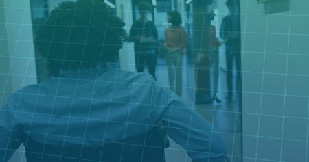 Navigating wheelchair user in light shirt through office hallway, with smartphone, rolling suitcase. Accessibility, inclusion, professional, mobility, diversity, collaboration, architectureの写真素材