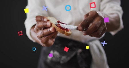 Spreading red jam on bread by cook in black apron on stage, with knife, colorful shapes. Culinary, gastronomy, gourmet, modern, vibrant, artistic, presentationの写真素材
