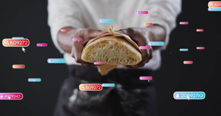 Displaying baker wearing apron holding halved bread in brown paper in studio, with digital tags. Artisan, bakery, digital, technology, culinary, foodie, modernの写真素材