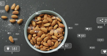 Displaying ceramic bowl holding almonds beside scattered almonds on tabletop, with overlay icons. Health, nutrition, snacking, organic, minimalist, digital interface, food photographyの写真素材