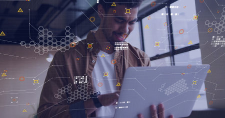 Tech professional holding silver laptop displaying overlaid data graphics in office with smartwatch. Futuristic, innovation, digital, coworking, productivity, modern, analyticsの写真素材