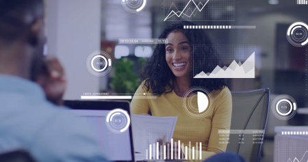 Presenting Hispanic woman holding printed reports at office desk, with laptop and data overlays. Business, collaboration, data analysis, professional, modern, technology, teamworkの写真素材