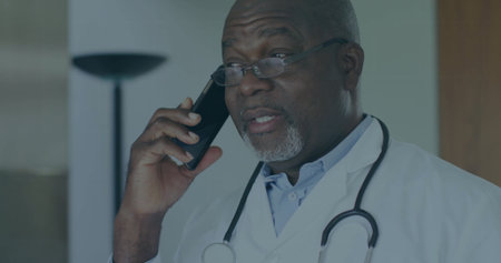 Speaking doctor wearing lab coat and eyeglasses holding smartphone in clinic with stethoscope. Healthcare, professional, consulting, communication, modern, wellness, seniorの写真素材