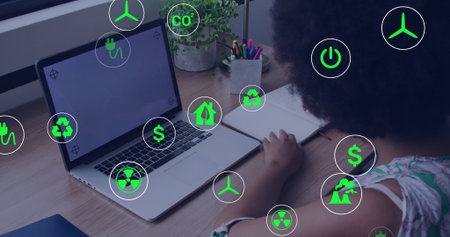 Writing African American woman in notebook at home desk, with laptop plant copy space. Sustainability, innovation, eco-conscious, workspace, renewable, technology, productivityの写真素材