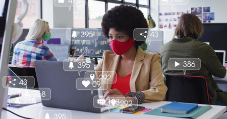 Collaborating masked colleagues sharing open office using laptops, with floating notification icons. Collaboration, teamwork, modern, productivity, corporate, communication, digitalの写真素材