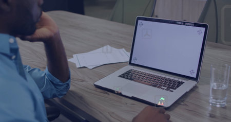 Man in blue shirt resting chin reviewing laptop in boardroom, with papers, water glass, copy space. Corporate, brainstorming, modern, professional, collaboration, leadership, focusの写真素材