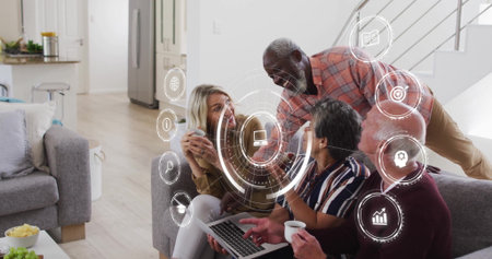 Collaborating four friends interacting with holographic icons on sofa in living room, with laptop. Collaboration, technology, innovation, modern interior, social interaction, digital interface, casual meetingの写真素材