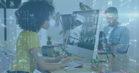 Typing office worker wearing yellow tee at open plan office desk, with desktop monitor, copy space....