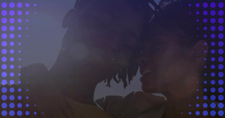 Leaning heads together couple wearing light jacket and t-shirt under clear sky, purple dot overlay....