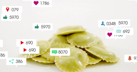 Floating social media icons circling pile of yellow ravioli squares on white surface, digital theme....