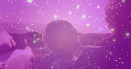 Cradling mother holding baby on rural roadside at sunset, with parked SUV and hooded baby garment. Family, rural, landscape, silhouette, warmth, bonding, wildernessの写真素材