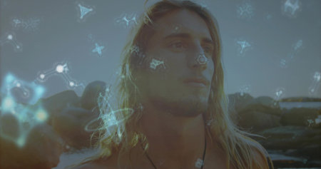 Standing shirtless male wearing cord necklace, gazing at horizon on rocky coast, with digital stars. Adventure, tranquility, meditation, surreal, minimalist, natural, introspectionの写真素材