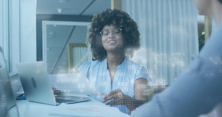 Speaking professional gesturing with digital overlay at office meeting table, with laptop, papers....