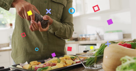 Seasoning home cook holding pepper grinder over baking tray at kitchen countertop, with fresh herbs. Culinary, health, preparation, rustic, fresh, cozy, ingredientの写真素材