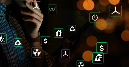 Standing man in plaid shirt holding tablet touching chin at office floating eco icons, copy space. Technology, innovation, analysis, sustainability, energy, environment, digitalの写真素材