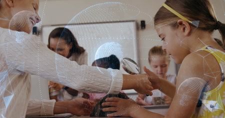 Guiding teacher and student examining rock specimen on table in classroom, with magnifying glass. Education, classroom, science, exploration, learning, discovery, teamworkの写真素材