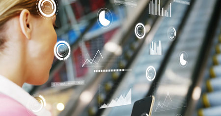 Holding smartphone businesswoman viewing floating data visuals at terminal escalators, copy space. Technology, analytics, innovation, corporate, urban, futuristic, professionalの写真素材