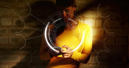 Using smartphone, woman in yellow shirt, dark cap viewing AR overlay against exposed brick wall....