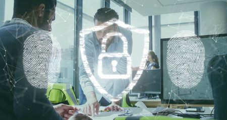 Collaborating coworkers leaning over documents in modern office, with security icons and monitors....