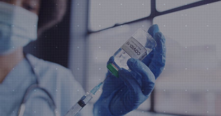 Drawing fluid by clinician's gloved hand in clinic, with COVID-19 vial, syringe and stethoscope. Medical, healthcare, vaccine, clinical, laboratory, vaccination, professionalismの写真素材