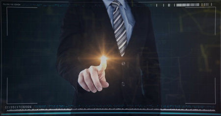Pointing executive wearing dark suit, tie touching glowing amber dot on interface wall in studio. Technology, innovation, data, digital, futuristic, corporate, networkingの写真素材