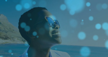 Smiling woman standing on coastal overlook with cat-eye sunglasses and striped shirt, copy space....