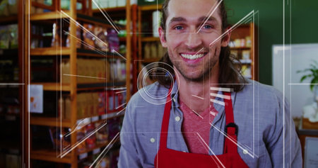 Smiling shop employee wearing red apron stocking wooden shelves in shop, showing clipped microphone. Retail, merchandising, rustic, cheerful, customer service, atmosphere, brandingの写真素材