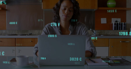 Working woman reviewing financial data in kitchen, with laptop coffee mug notebook pen and tablet. Technology, finance, homeoffice, productivity, modern, digital, casualの写真素材