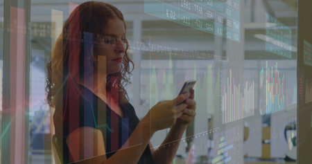Holding smartphone, analyst projecting data charts in open-plan office, with glass partitions....