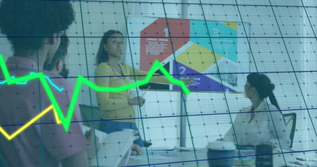 Presenting woman in yellow top and jeans explaining graphs on flip chart in office meeting room. Collaboration, business, teamwork, corporate, analysis, modern, discussionの写真素材