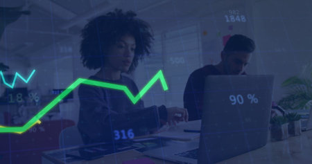 Two professionals analyzing data in open-plan office, with laptop, documents and line graph overlay. Collaboration, teamwork, data, innovation, productivity, modern, businessの写真素材