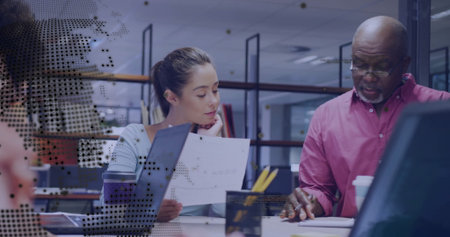 Man in pink shirt pointing with woman in blue top listening at office desk, digital overlay. Collaboration, teamwork, communication, innovation, modern, professional, productivityの写真素材