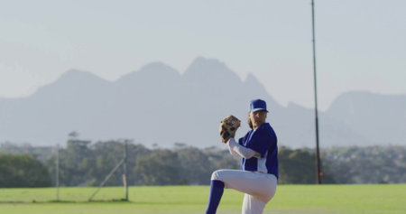 Pitching player in blue uniform preparing to throw ball on grass field with glove, copy space. Athletics, sport, competition, outdoor, energetic, performance, activeの写真素材