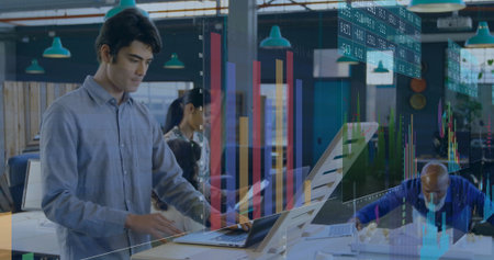 Native-American analyst typing on laptop at standing desk in office, showing charts, copy space. Collaboration, data visualization, teamwork, modernoffice, professional, digitalcharts, analyticsの写真素材