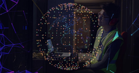 Tech wearing safety vest and headphones monitoring servers in server room, with globe, copy space. Technology, cybersecurity, data center, network infrastructure, digital connectivity, system administration, it professionalの写真素材