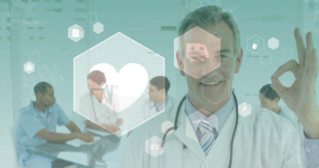 Gesturing senior doctor making OK sign in meeting room, with hex icons, stethoscope, copy space. Medical collaboration, healthcare technology, clinical environment, digital health, multidisciplinary team, modern medicine, medical innovationの写真素材