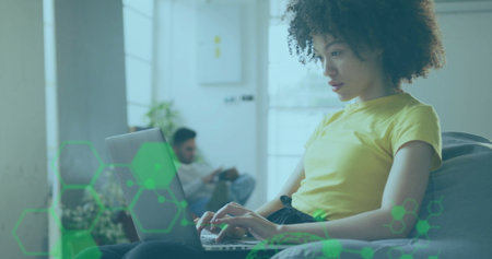 Typing woman using laptop in living room, with potted plant and man using smartphone, copy space. Cozy, modern, minimalist, collaboration, technology, leisure, homeの写真素材