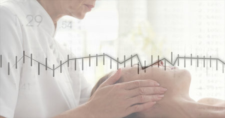 Leaning therapist massaging client face at spa room, with white uniform, padded table and towel. Relaxation, serenity, wellness, skincare, massage, therapeutic, naturallightの写真素材