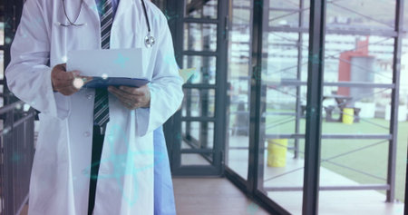 Doctor checking records and holding blue clipboard in clinic corridor, with stethoscope, copy space. Medical, healthcare, professionalism, modern, hospital, urban, clinicalの写真素材