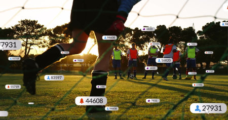 Goalkeeper in blue jersey kicking soccer ball on pitch at sunset. Athletic, team, outdoor, dynamic,...