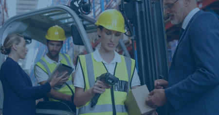 Woman in hard hat vest scanning cardboard box with scanner at depot forklift pallet racks tablets. Logistics, warehouse, inventory, teamwork, industrial, productivity, technologyの写真素材
