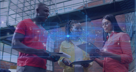 Three coworkers reviewing papers, tablet and holographic interface in workshop, with vehicle hood. Collaborative, industrial, modern, innovation, teamwork, engineering, technologyの写真素材