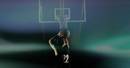 Standing basketball player raising ball at free-throw line in hazy arena, with hoop, net, jersey 22. Athletic, energetic, dynamic, competitive, sports, dramatic, disciplinedの写真素材