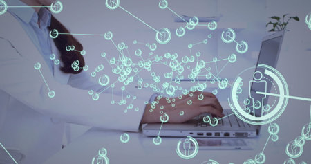 Typing Chinese woman in lab coat using laptop at office desk with network icons, copy space. Technology, innovation, biomedical, healthcare, communication, professional, futuristicの写真素材