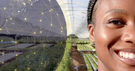 Smiling Black woman standing inside greenhouse, with seedling benches and network globe, copy space. Sustainability, biotechnology, eco, innovation, horticulture, vibrant, environmentalismの写真素材