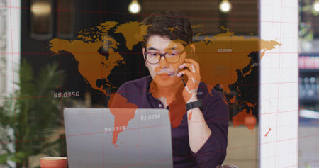 Asian man wearing glasses juggling smartphone and laptop at cafe, with coffee mug and map overlay....