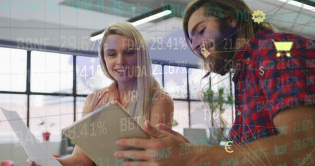 Reviewing coworkers examining report and tablet in modern open plan office, with data overlays....