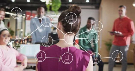 Presenting woman in purple sleeveless blouse addressing team in office with laptop tablet overlay. Collaboration, teamwork, modernity, innovation, connectivity, diversity, professionalの写真素材
