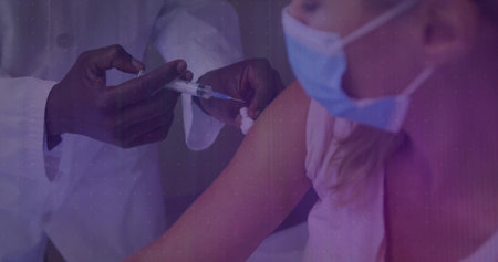 Injecting nurse wearing gloves administering vaccine into exposed upper arm in clinic, with syringe. Medical, vaccination, healthcare, immunization, clinical, protective, sterileの写真素材