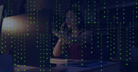 Talking on smartphone Asian worker in red blouse typing on keyboard in office with binary overlay....